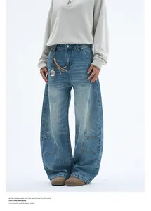 Detail of light blue wide-leg jeans featuring curved seams and a leather tassel pendant