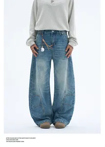 Detailed view of light blue washed denim jeans featuring structural curved seams and distressed texture