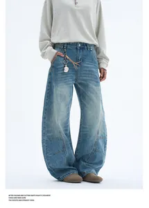 Detail view of retro blue washed jeans featuring curved seams and a silver metal charm accessory