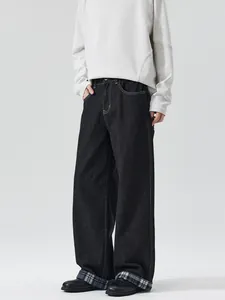 Black wide-leg raw denim jeans with white contrast stitching and plaid cuffed hems