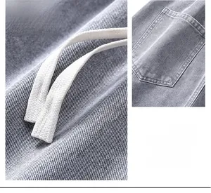 Dettaglio del tessuto denim grigio con coulisse bianche e cuciture sulle tasche