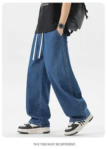 Dettaglio di jeans blu scuro con coulisse bianca e taglio ampio a gamba larga
