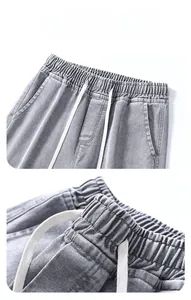Dettaglio dei pantaloni in denim grigio con vita elastica e coulisse bianche regolabili