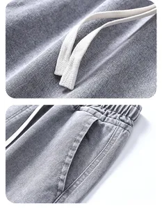 Dettaglio dei pantaloni in twill grigio con elastico in vita e coulisse bianca