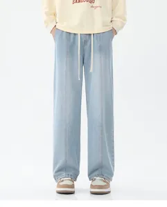 Détail d'un jean large bleu clair avec coutures verticales et taille à cordon serrage