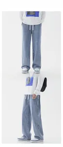 Detail of light blue wide-leg jeans with drawstring waist and washed denim texture