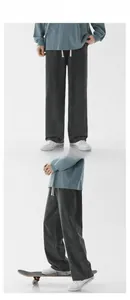 Detail of dark gray washed straight-leg pants with white drawstring and elastic waistband