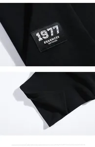 Détail d'un polo noir en maille piquée avec un écusson carré brodé 1977 essence