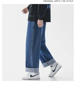 Detail of dark blue denim jeans featuring wide cuffed hems and sturdy cotton fabric texture