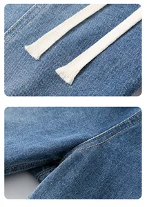 Détails de jeans bleus montrant le cordon de serrage blanc et les surpiqûres orange
