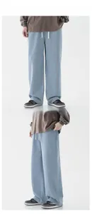 Detail of light blue denim wide leg pants showing drawstring waist and loose fit design