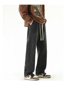 Close-up of baggy dark grey denim jeans featuring white drawstring and washed texture