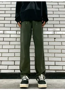 Detail view of olive green double-knee work pants with metal rivets and canvas texture