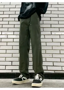 Detailed view of olive green double-knee work pants with silver rivet reinforcements
