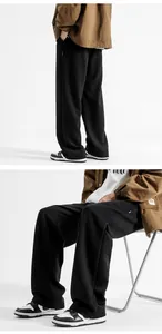 Détail du pantalon large noir à coupe ample montrant le drapé du tissu et la coupe droite