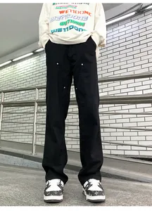 Detail of black double-knee work pants with metal rivets and utility pockets