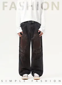 Dettaglio di jeans a gamba larga usurati con finitura grigio lavato e texture a pieghe