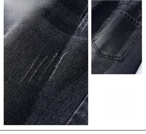 Macro detail of dark grey denim jeans showing distressing, pocket and twill texture