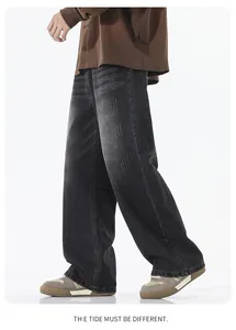 Detail of loose-fit black grey washed denim jeans featuring vintage whiskers and wide-leg cut