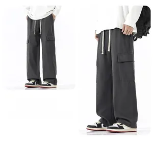 Détail d'un pantalon cargo gris foncé avec coupe large, poches à rabat et cordon de serrage
