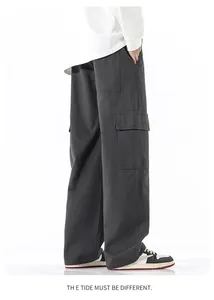 Détail d'un pantalon cargo gris foncé avec plusieurs poches et une coupe large en toile coton