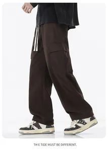 Détail d'un pantalon cargo marron ample montrant les poches latérales et le cordon blanc