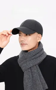 Detail of gray wool baseball cap with ear flaps and matching knit scarf for winter warmth