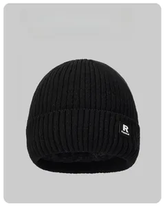 Detail of black ribbed knit beanie featuring R FASHION leather patch and warm fleece lining