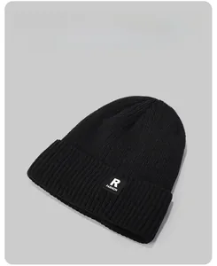 Detail view of black knit beanie featuring a rectangular R patch and double layer cuff style