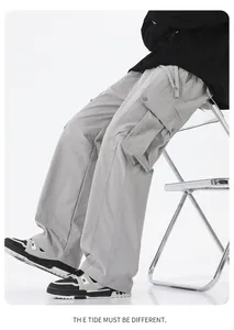 Detail of loose-fit grey technical cargo pants featuring large utility side pockets