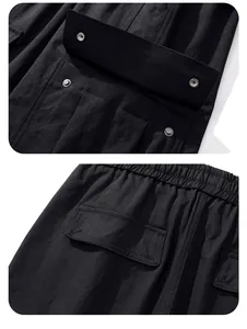 Detail view of black outdoor cargo pants featuring snap button flap pockets and elastic waist