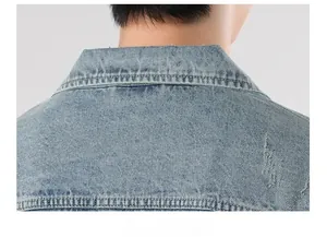 Macro detail of washed denim jacket collar featuring distressed frayed hole texture