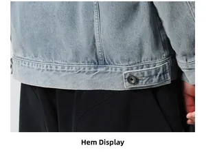 Detail of light blue washed denim jacket hem featuring black metal adjustment button