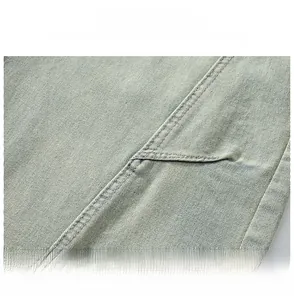 Macro detail of washed light blue denim fabric showing twill texture and reinforced stitching