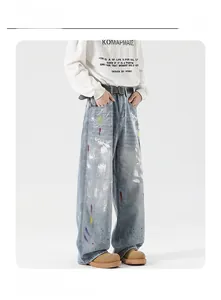 Detailed view of light blue wide-leg jeans with artistic multicolor paint splatter design
