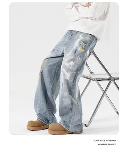 Detail view of light blue washed jeans featuring multicolor paint splatters and ripped holes