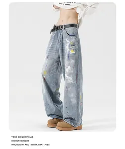 Detailed close-up of light blue denim with artistic colorful paint splatters and distressing