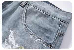 Macro detail of light blue washed denim featuring vintage graffiti print and metal rivets