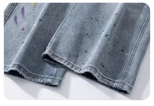 Macro detail of light blue denim cuffs featuring artistic multi-color paint splatter design