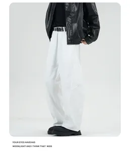 Detail of white wide-leg trousers paired with black jacket and studded leather belt