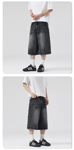 Close-up of vintage washed black denim shorts with whisker distressing and loose fit cut