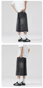Detail view of washed dark grey denim shorts with lightning pattern and baggy wide-leg fit