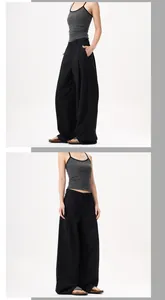 Dettaglio dei pantaloni neri a vita alta con gamba larga e design a pieghe drappeggiate