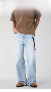 Detail of light blue straight denim jeans with beaded tassel and natural whiskering