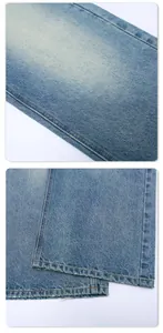 Detail of light blue washed denim fabric with distressed hem and precision stitching