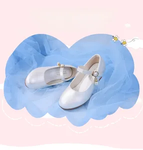 Détail de chaussures Mary Jane blanches avec pendentif perle et boucle dorée