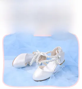 Detailed view of white princess shoes for girls with pearl straps and bow decoration