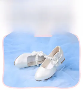 Detail of white Mary Jane girl shoes with pearl strap, bow accent and non-slip sole