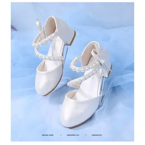 Close-up of girls white princess shoes featuring pearl straps and bow details