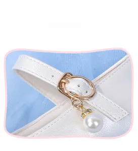 Détail de chaussure princesse crème avec boucle en métal doré et pendentif en perle